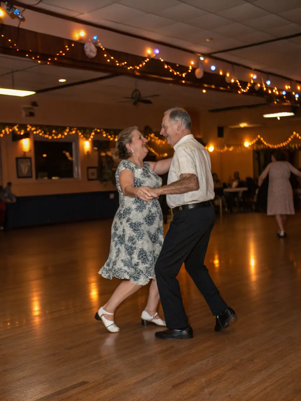 A candid photo capturing the lively atmosphere of a country dance social event, with people of all ages and skill levels enjoying themselves on the dance floor. A live band is playing in the background.